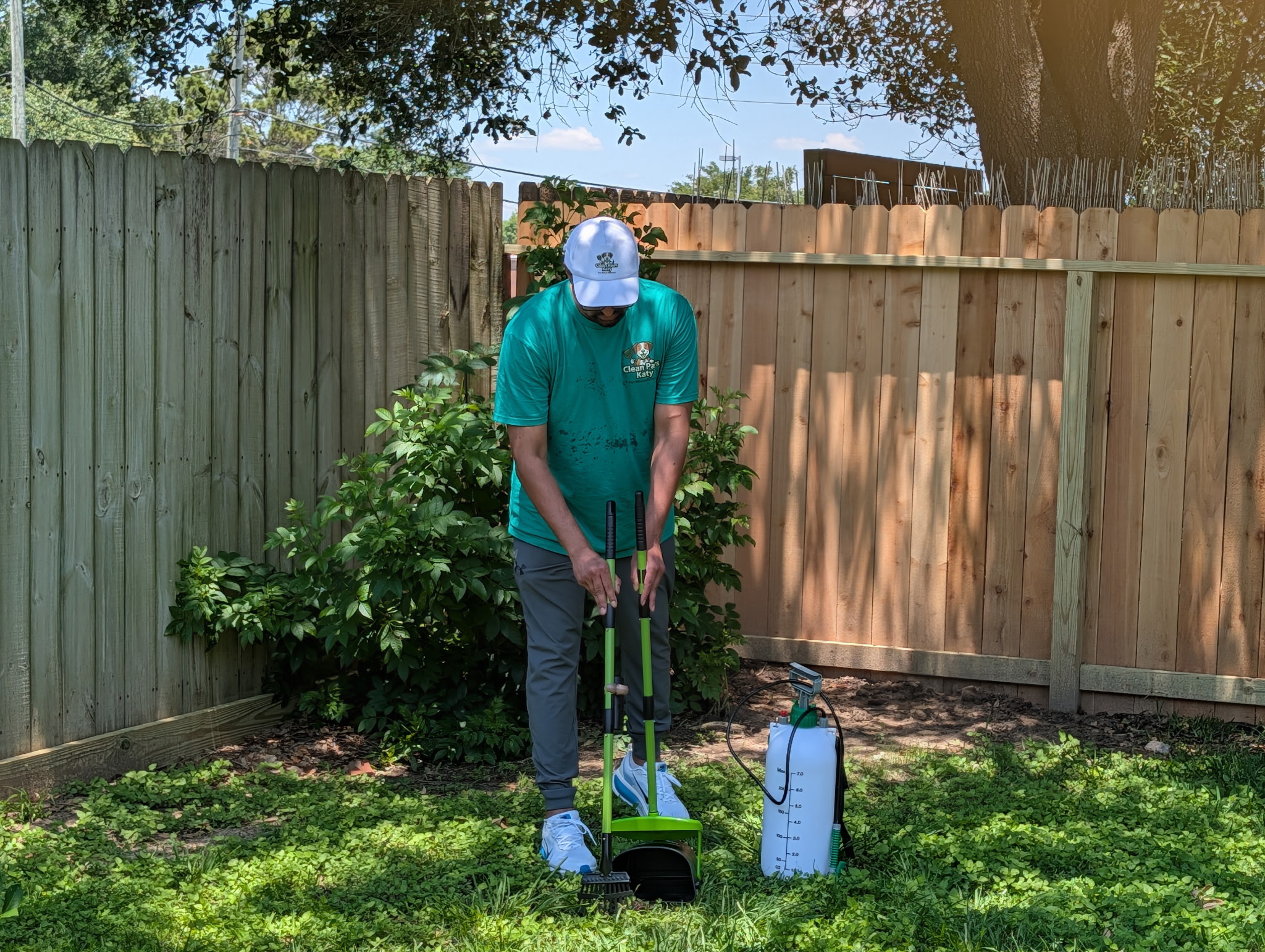Sam scooping pet waste in a Katy backyard in Clean Paws Katy uniform